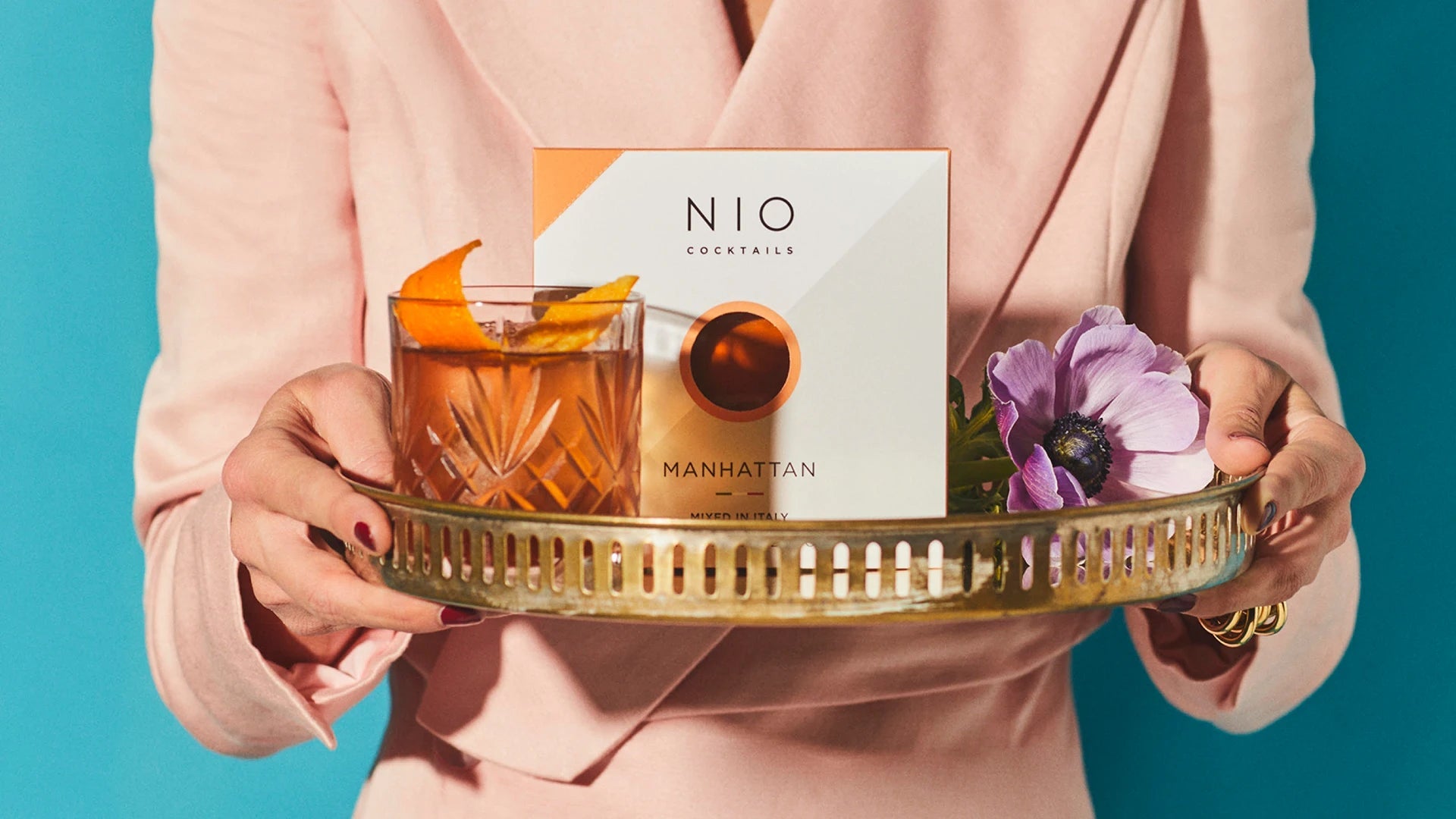 elegant lady in pink serving a nio cocktail manhattan on a tray